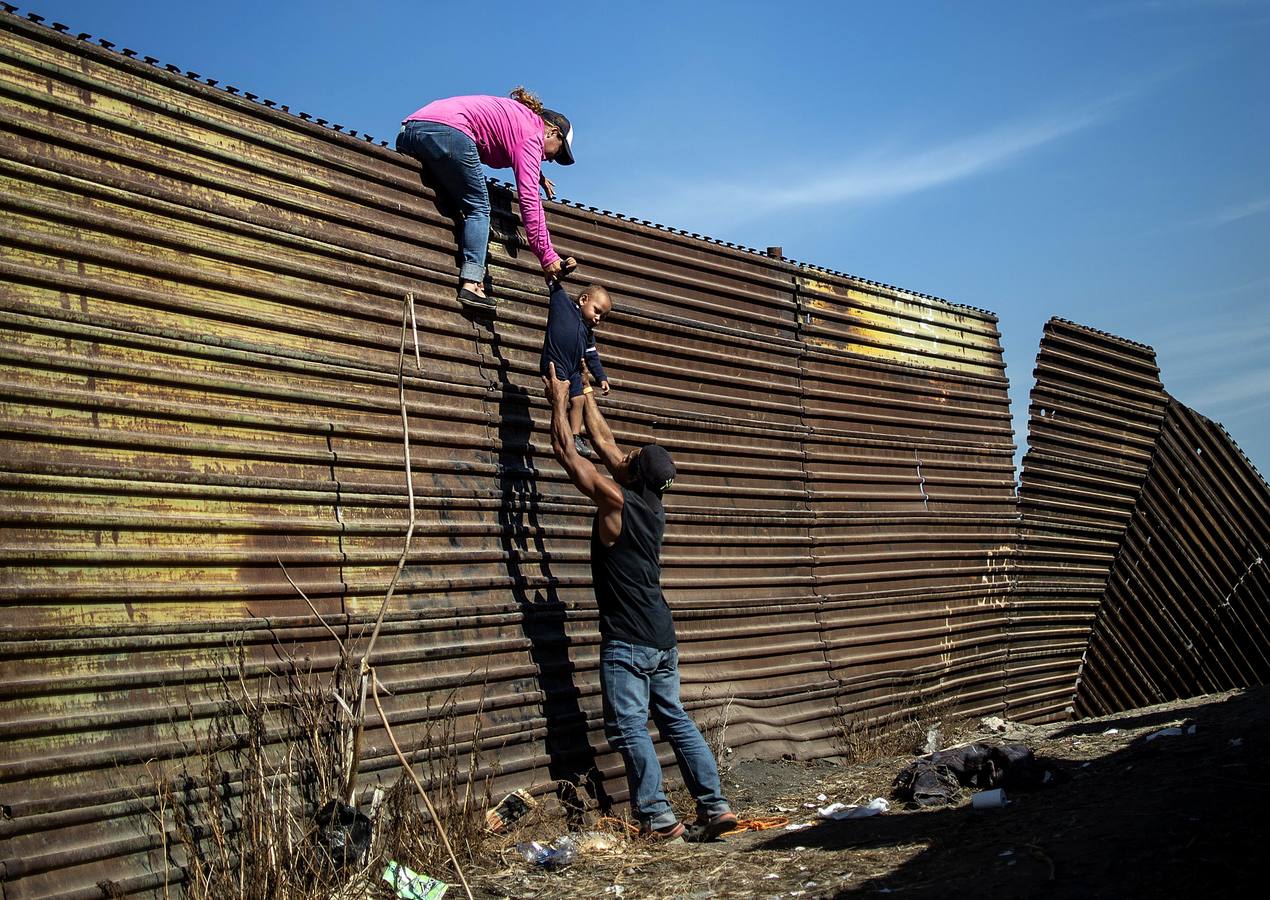 Un grupo de migrantes centroamericanos trepa la valla fronteriza entre México y Estados Unidos, cerca del cruce fronterizo de El Chaparral, en Tijuana.