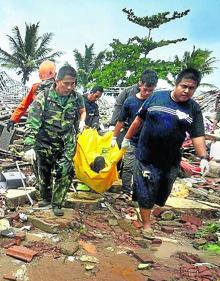 Imagen secundaria 2 - Vecinos de Pandeglang abandonan en motocicletas sus viviendas arrasadas por el agua. Abajo, los equipos de rescate recuperan los cuerpos de las víctimas.