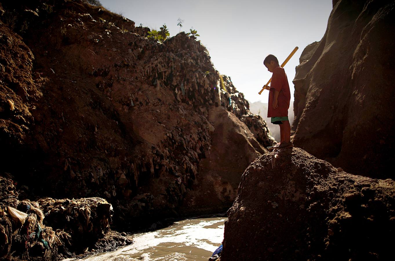 'La Mina', en la ciudad de Guatemala, se encuentra al fondo de un barranco atravesado por un río. Centenares de personas se afanan cada día entre sus aguas contaminadas, bajo la amenaza de deslizamientos y enfermedades, para tratar de encontrar objetos o chatarra con la que ganarse la vida. Algunos utilizan imanes para atraparlos, otros lo hacen a mano, introduciendo su cuerpo directamente en el agua, convertida en basurero. Si hay suerte pueden conseguir unos 20 dólares, el doble del salario mínimo. En ocasiones hasta es posible hallar un anillo o un pendiente de oro.