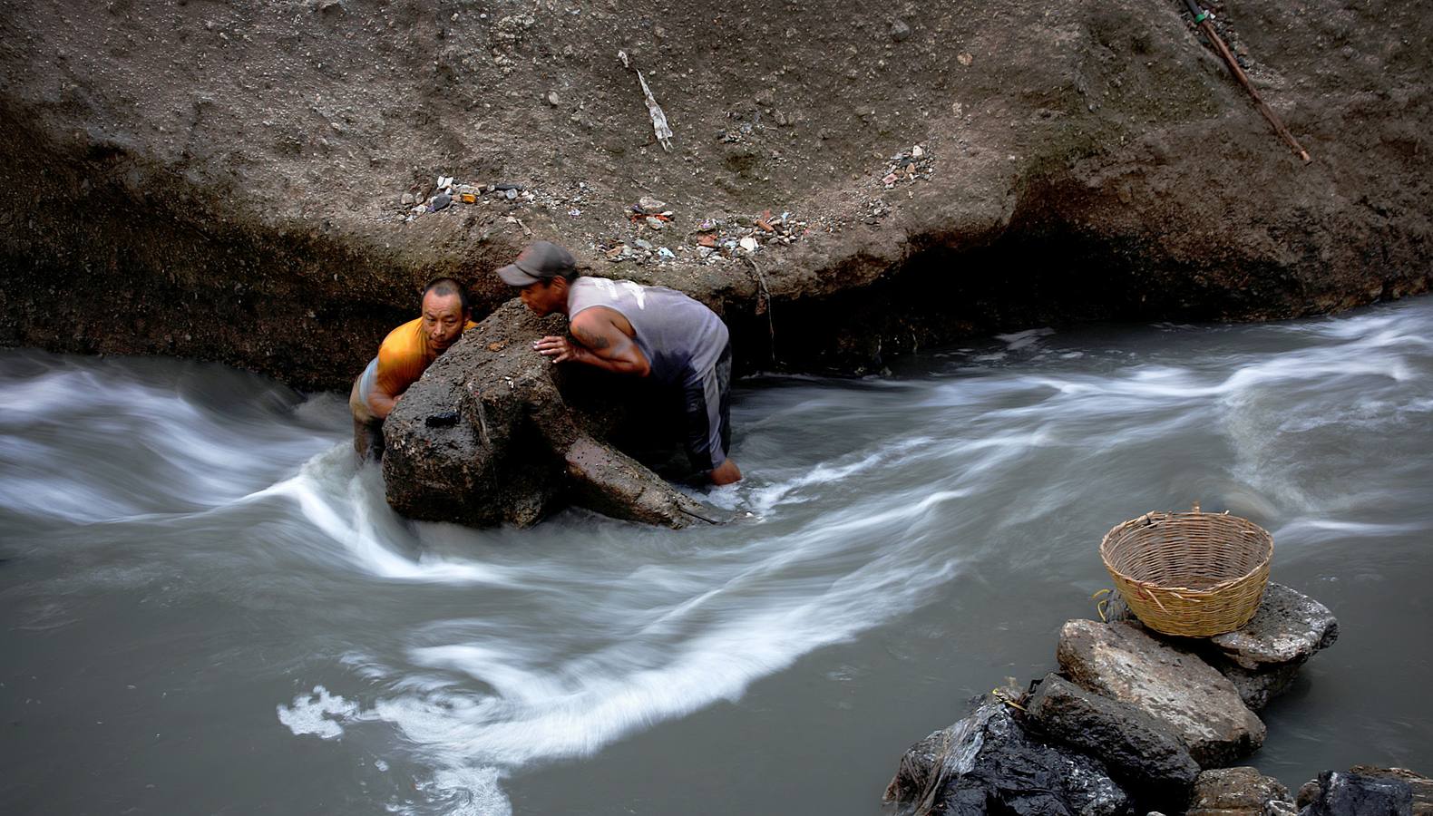 'La Mina', en la ciudad de Guatemala, se encuentra al fondo de un barranco atravesado por un río. Centenares de personas se afanan cada día entre sus aguas contaminadas, bajo la amenaza de deslizamientos y enfermedades, para tratar de encontrar objetos o chatarra con la que ganarse la vida. Algunos utilizan imanes para atraparlos, otros lo hacen a mano, introduciendo su cuerpo directamente en el agua, convertida en basurero. Si hay suerte pueden conseguir unos 20 dólares, el doble del salario mínimo. En ocasiones hasta es posible hallar un anillo o un pendiente de oro.