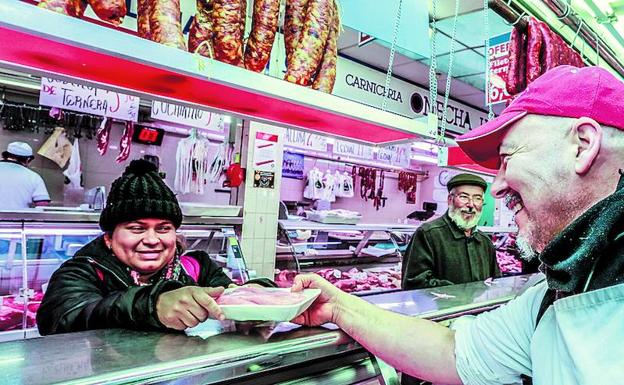 Un carnicero atiende a un cliente en el mercadillo de El Ensanche.