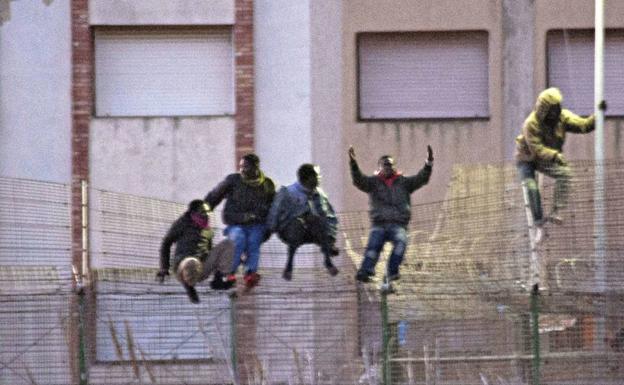 Inmigrantes encaramados en la valla de Melilla, en una imagen de archivo.