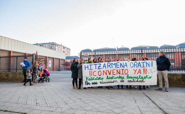 Trabajadores, con una pancarta de protesta en la puerta de un colegio concertado. 