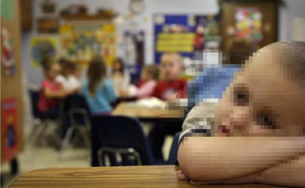 Un niño, ajeno a la información, sobre el pupitre de la escuela.