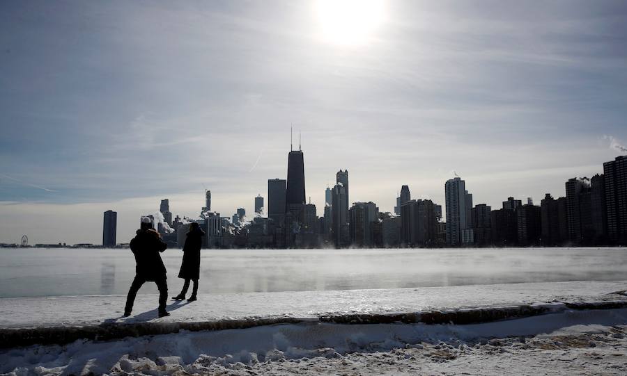 Una pareja se toma fotos con el skyline de Chicago de fondo, mientras el vapor se eleva desde los edificios de la ciudad.