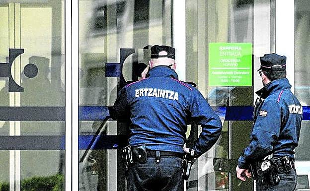 Dos ertzainas miran a través de la puerta de Santiago.