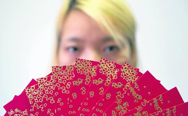 Una joven china muestra una docena de 'hongbao', en los que es costumbre meter dinero a modo de aguinaldo para los familiares.