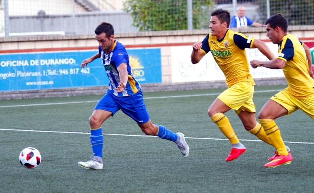 Aranda trata de despejar el balón presionado por dos jugadores del Izarra. 