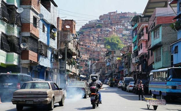 Imagen principal - Arriba, una vista del cerro José Félix Ribas, una de las favelas más grandes de América Latina. A la izquierda, Enrique, cuñado. A la derecha, un vecino. 