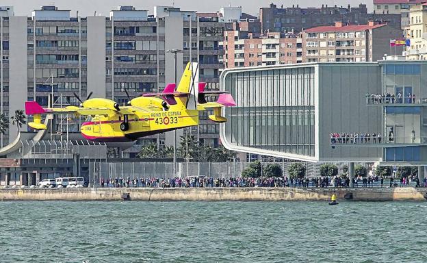 Helicópteros e hidroaviones que participaban en la extinción de los fuegos entraron una y otra vez a la bahía de Santander para cargar agua durante toda la jornada.
