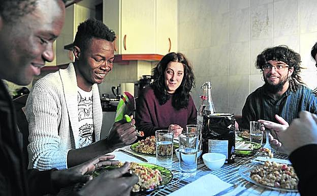 Unos inmigrantes subsaharianos disfrutan de una comida como invitados en casa de una familia en Vitoria. 