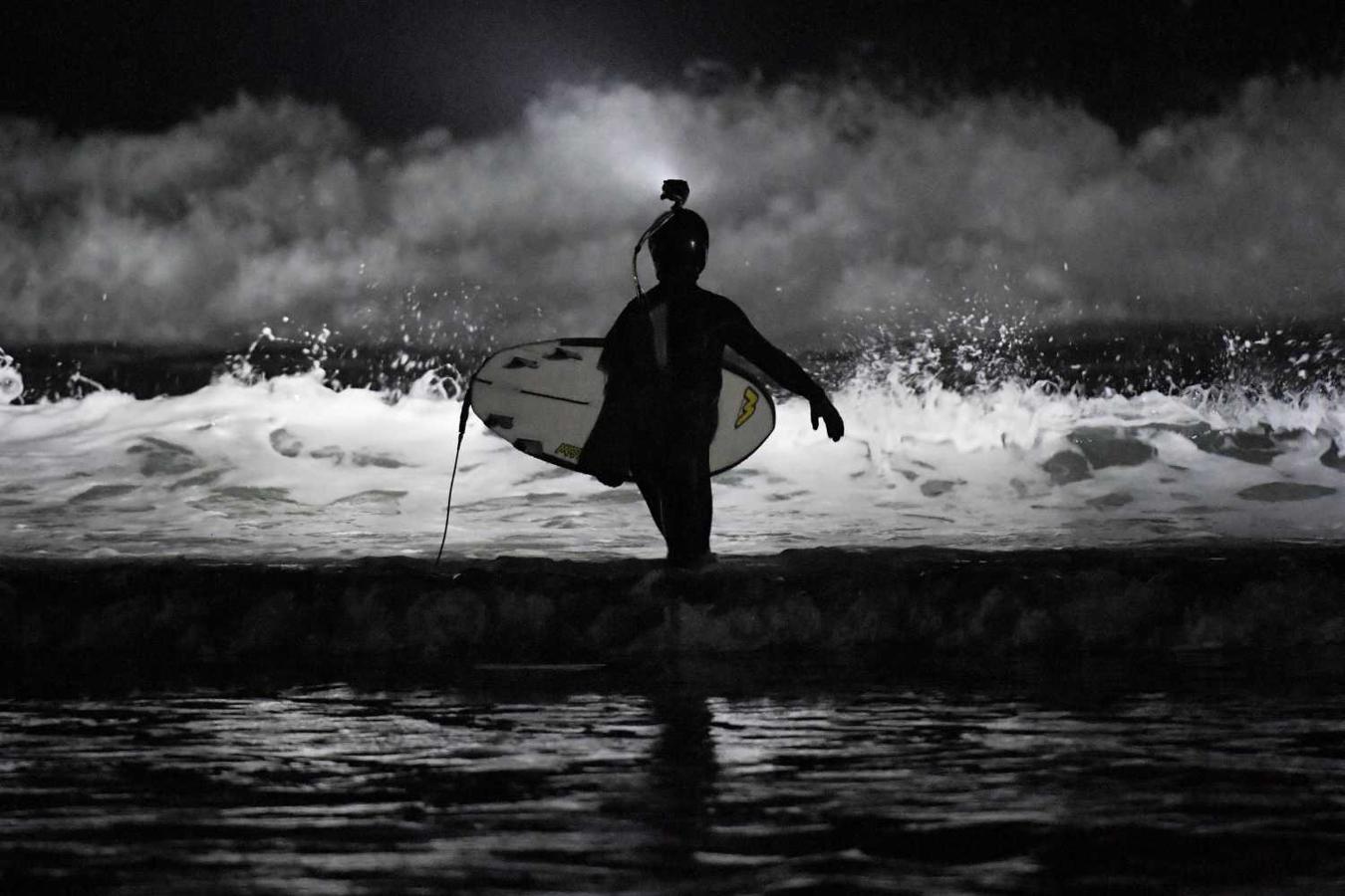 Los surfistas Yann Le Her, Alan, Yohann, Robin y Damien desafían el frío y la oscuridad en una sesión de surf nocturno en la playa del Cabo Fréhel, Bretaña