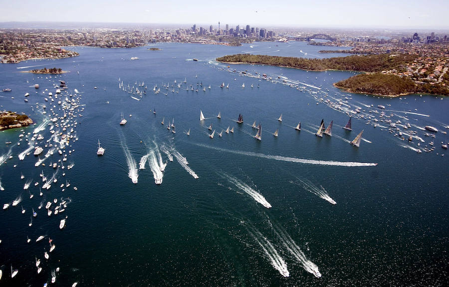 La flota de 85 yates cruza la línea de salida en el puerto de Sydney durante el inicio de la carrera de yates de Sydney a Hobart.