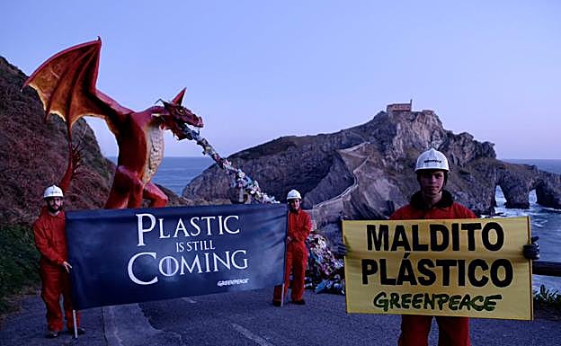 Tres activistas de la organización medioambientalista despliegan sus pancartas junto al dragón.