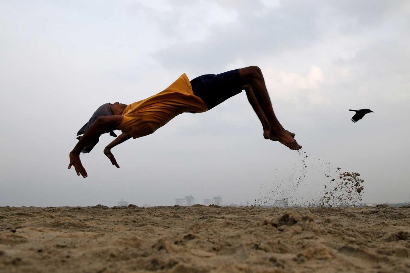 Joven practica un salto mortal en una playa en Kochi, India