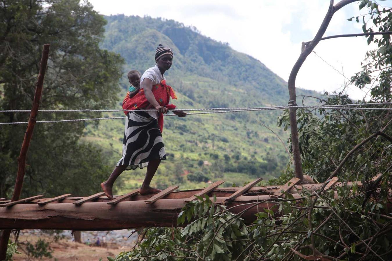 Una mujer y su bebé cruzan un puente improvisado tras el paso del ciclón Idai en Chimanimani, Zimbabue