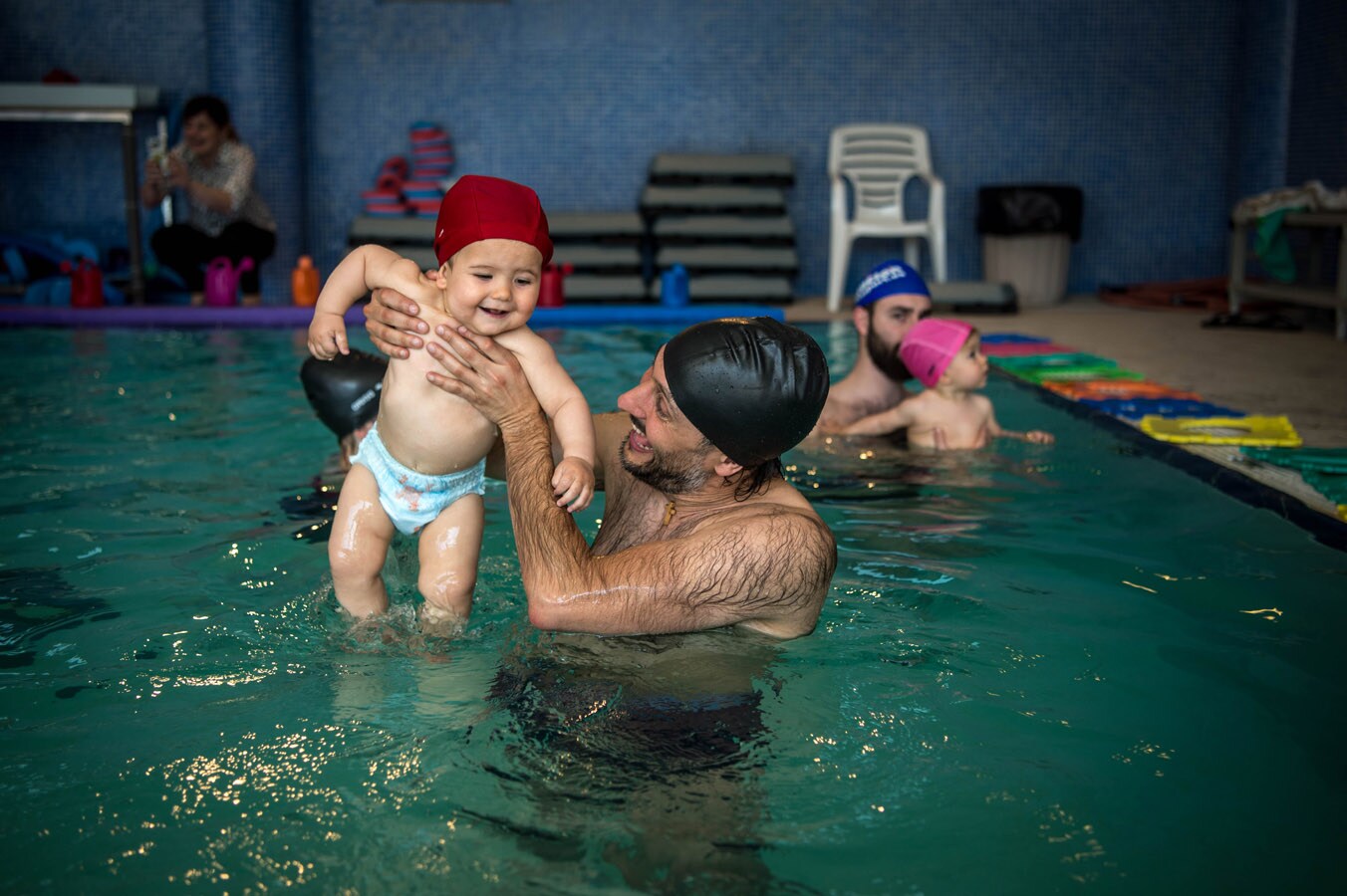 Einar, de 10 meses, y su aita Álvaro, juegan en la piscina.