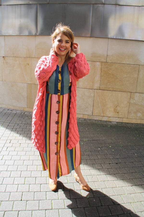 Un vestido coral a rayas con chaqueta de punto, un look divertido y alegre.