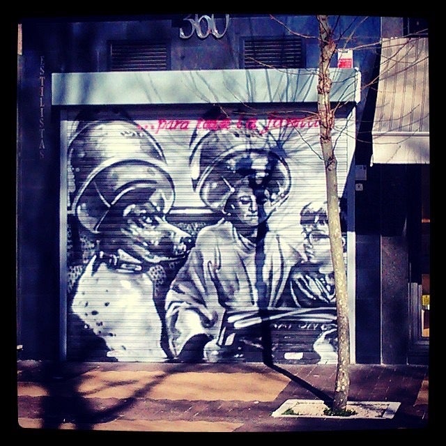 Una mujer, un niño y un perro son los protagonistas de este mural pintado sobre la persiana de una peluquería ubicada en la calle Los Herrán.