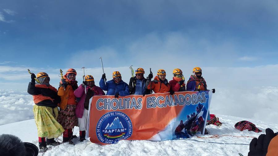 Ocho mujeres portan una pancarta de la Asociación Andina de Promotores en Aventura y Montaña deBolivia (AAPTAM) en una de las cimas.