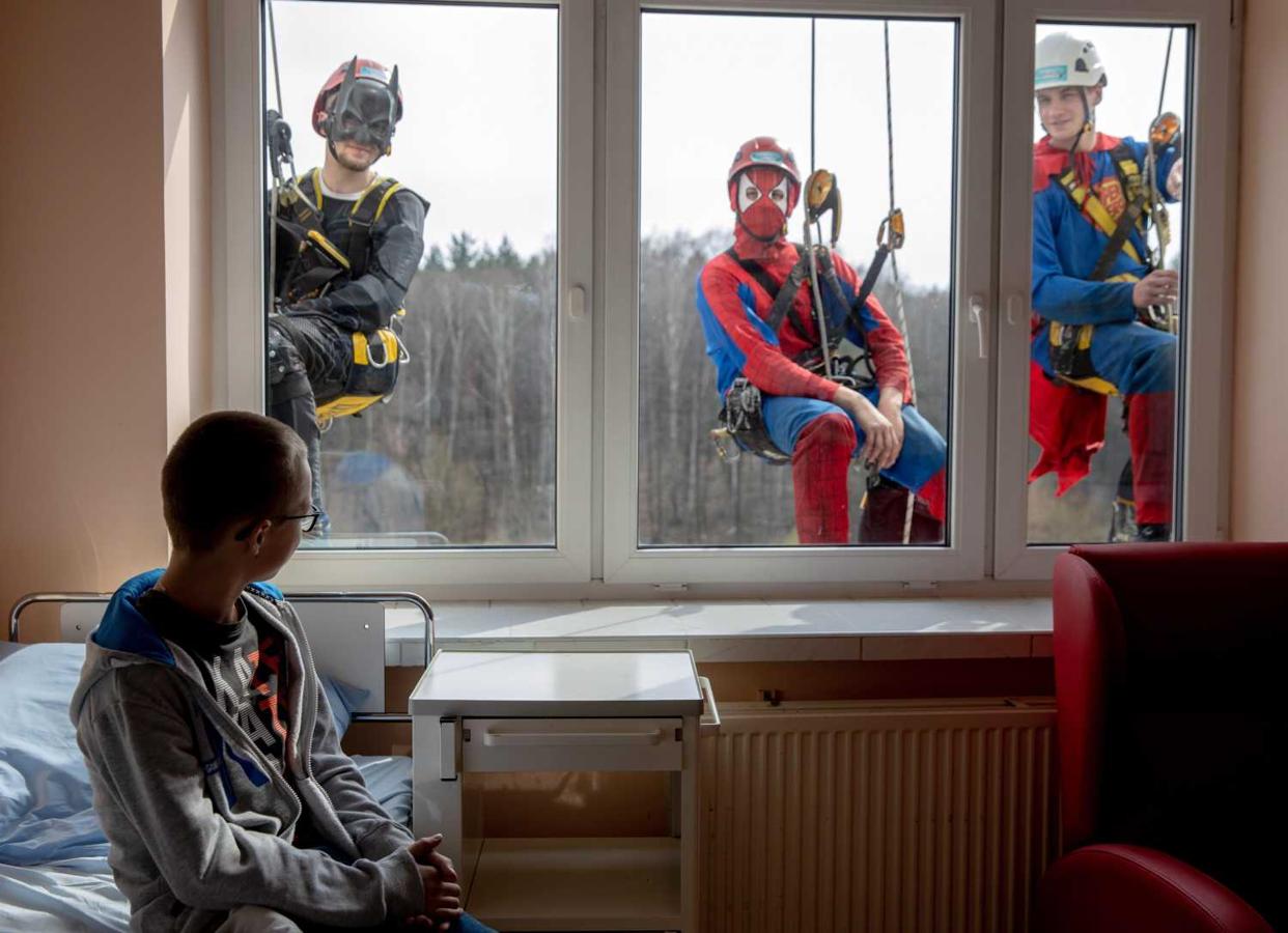 Un niño ingresado en el hospital infantil Juan Pablo II de la Alta Silesia en Katowice, Polonia, observa a dos hombres vestidos de superhéroes que limpian las ventanas