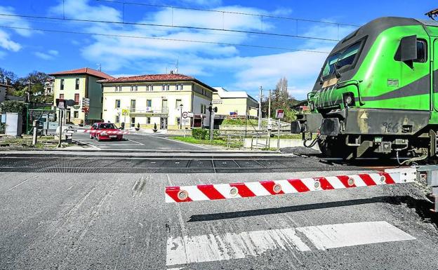 Los coches esperan a que pase un tren por el paso a nivel de Pobes.