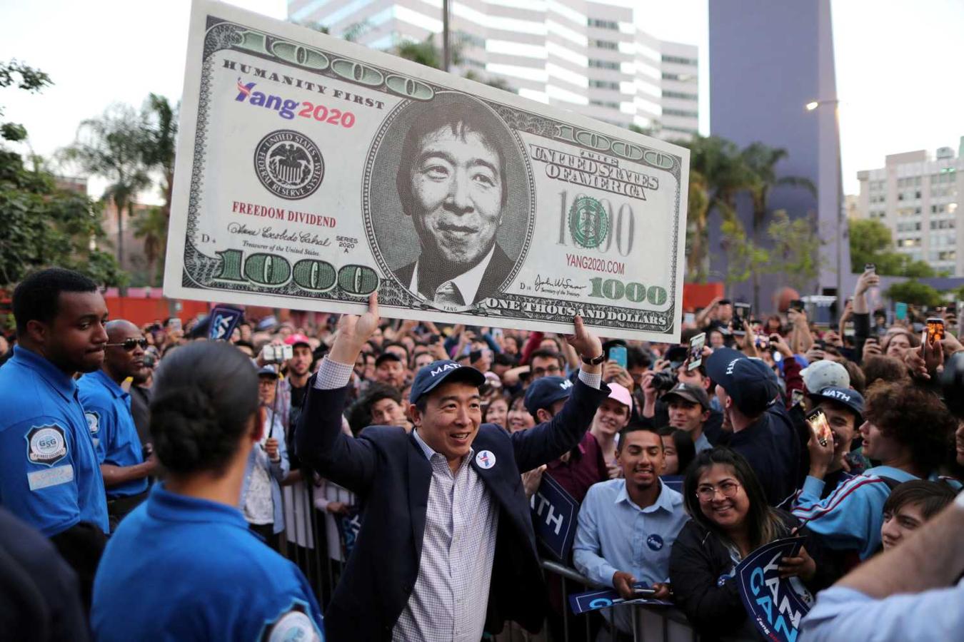 Andrew Yang, candidato demócrata a la presidencia de Estados Unidos, muestra un cartel que el representa en un billete de 1000 dólares, durante un acto en Los Angeles, California 