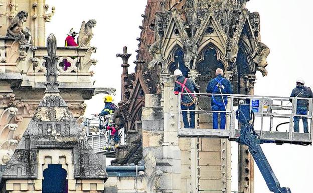 Bomberos y técnicos examinan los desperfectos causados por el fuego en Notre Dame.