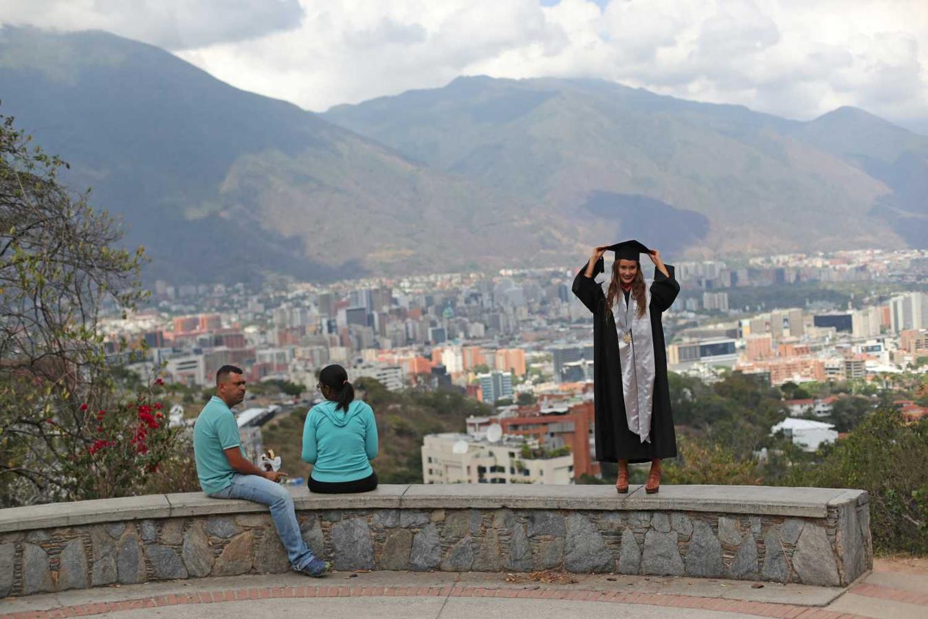 Génesis González arregla su birrete antes de posar para una fotografía en el mirador de Valle Arriba en Caracas, Venezuela,. El padre de Genesis, Rafael, dijo: "Mi hija es graduada de Psicología de la Universidad Católica Andrés Bello, a pesar de la adversidad. Debemos celebrar estas cosas”.