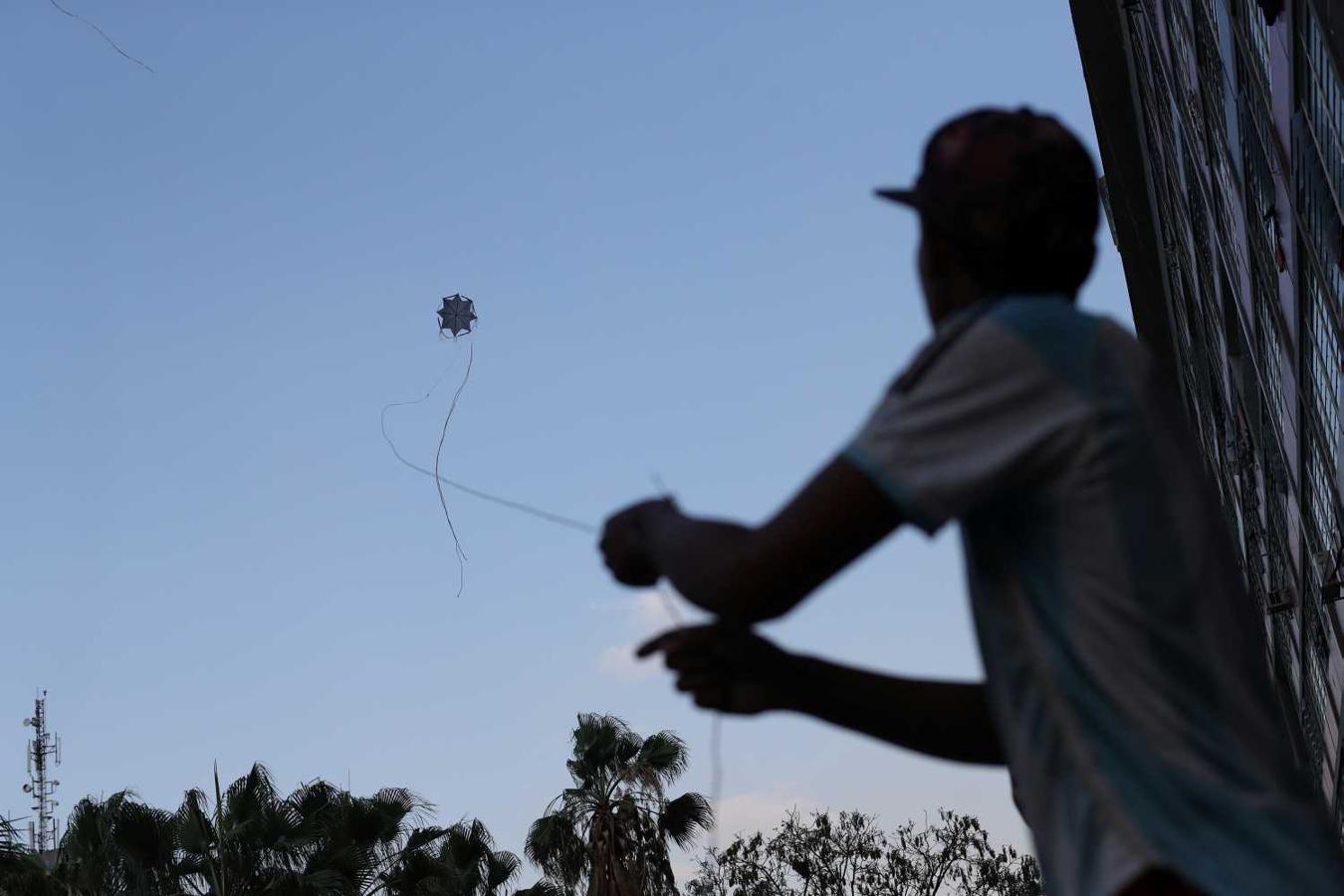 Un joven vuela una cometa casera junto al proyecto de vivienda Gran Misión Vivienda en Caracas. Los niños hacen sus propias cometas con una bolsa de plástico, palos y una línea de nylon. "Lo más caro es el cono de nylon, que cuesta unos 10000 Bolívares (aproximadamente 3 dólares estadounidenses)", dijo Luis Flores.