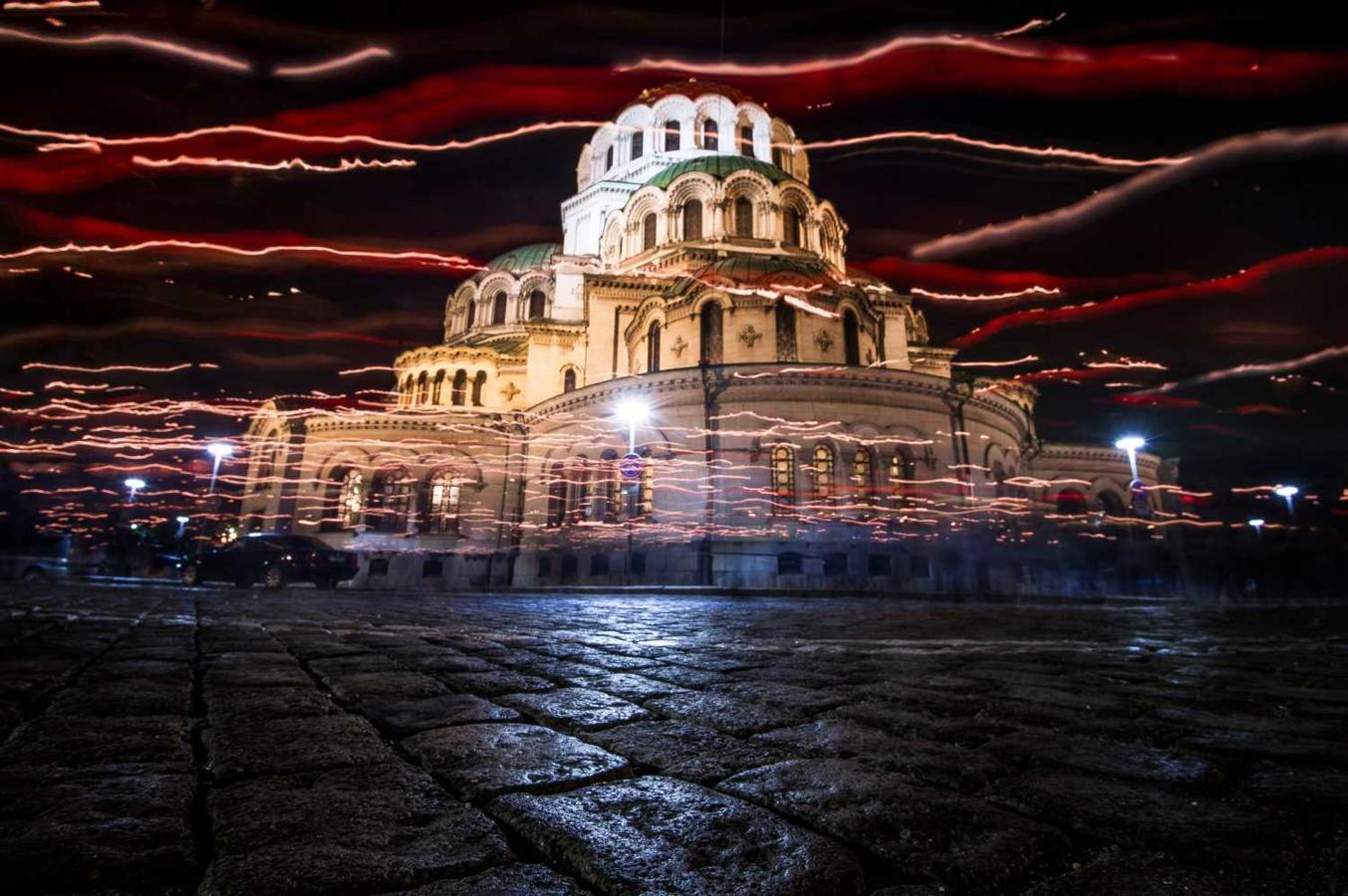 Fotografía de larga exposición, tomada el 27 de abril de 2019, los fieles búlgaros ortodoxos caminan sosteniendo velas durante una misa de Pascua en la misa de medianoche frente a la catedral de Alexander Nevski, con sus cúpulas doradas en Sofía, Bulgaria