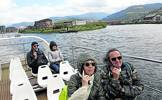Turistas contemplan la ría desde la cubierta del Bilboats mientras escuchan la explicación con audioguías.