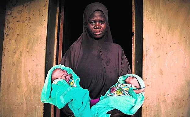 De dos en dos. Una mujer musulmana muestra a sus gemelos varones, de solo cuatro días de vida, a la puerta de su casa, en Igbo Ora.