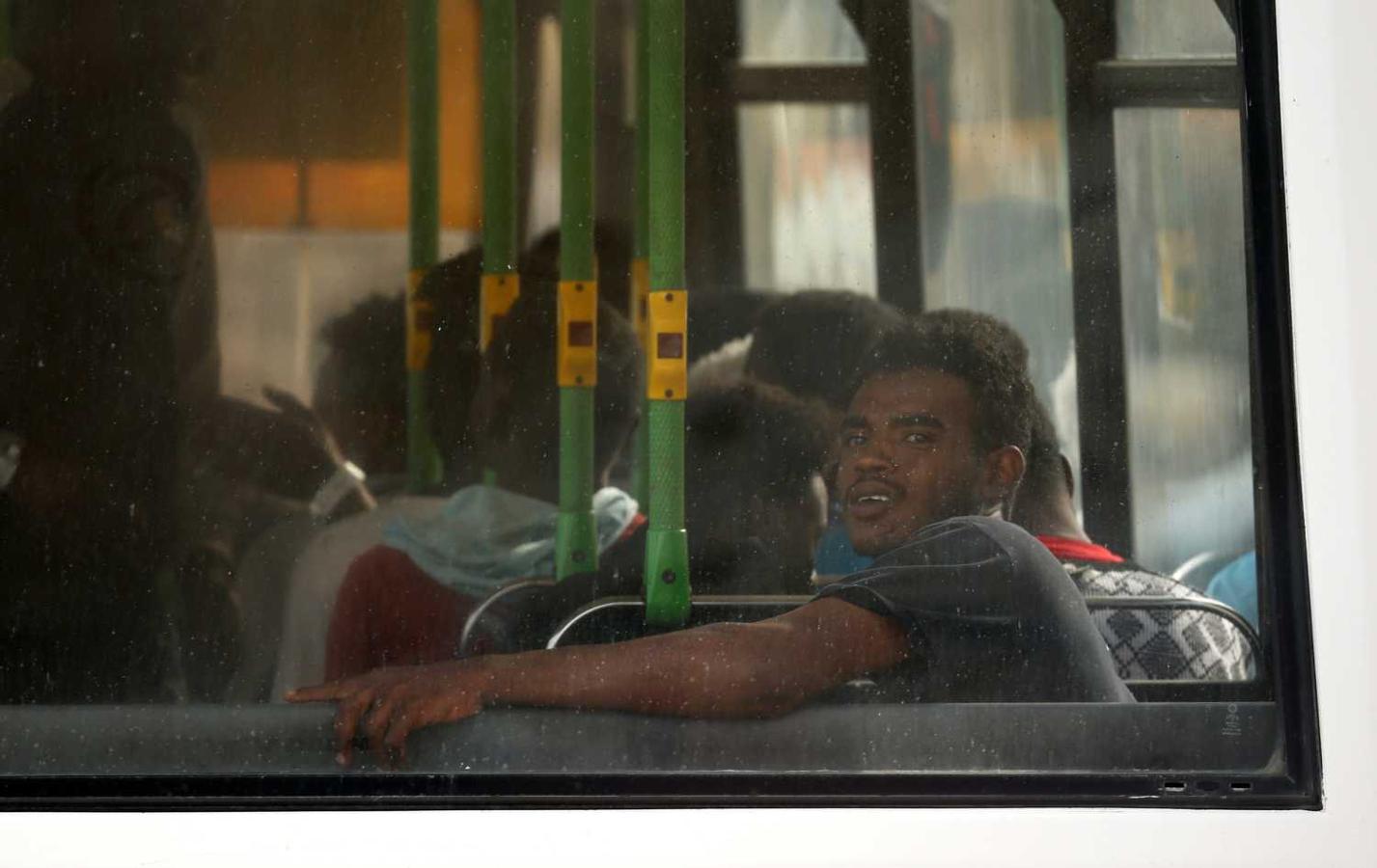 Los migrantes sentados en un autobús de la policía después de desembarcar de un bote patrullero de las Fuerzas Armadas de Malta en su base del puerto de La Valeta