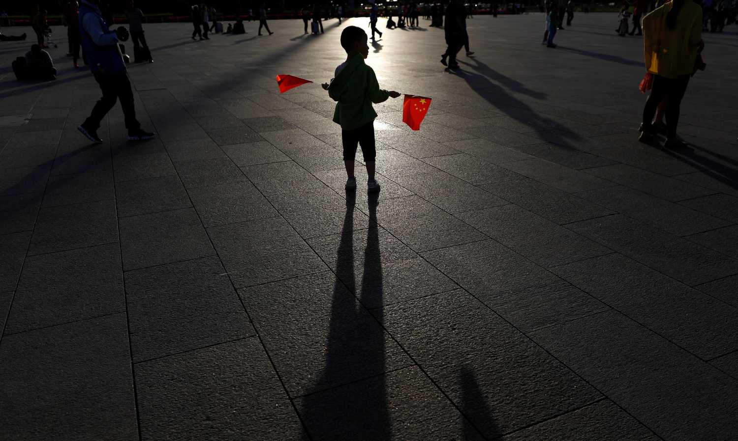 Un niño sostiene dos banderines en la plaza de Tiananmen en Pekín, a pocos días del aniversario de los incidentes de Tiananmen