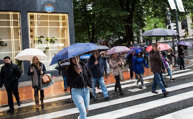 Un grupo de personas se protegen de la lluvia con paraguas y chubasqueros en Bilbao.