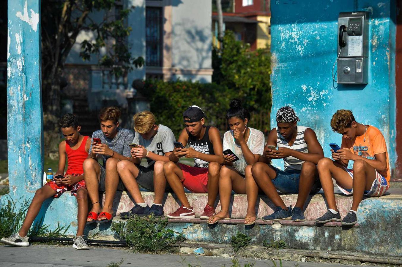 Jóvenes cubanos consultan sus móviles en La Habana