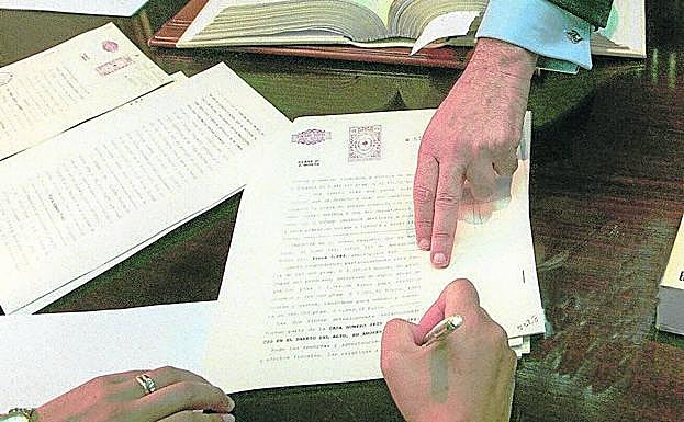 Un cliente firma ante un notario la escritura de un crédito hipotecario.