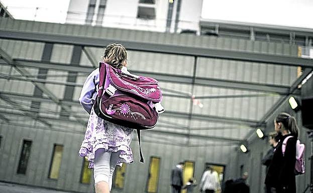 Una niña atraviesa el patio cargada con la mochila camino de clase.