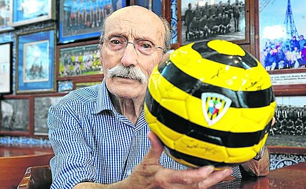 Demófilo Sánz sostiene un balón del Barakaldo con las fotografías de antiguas plantillas detrás.