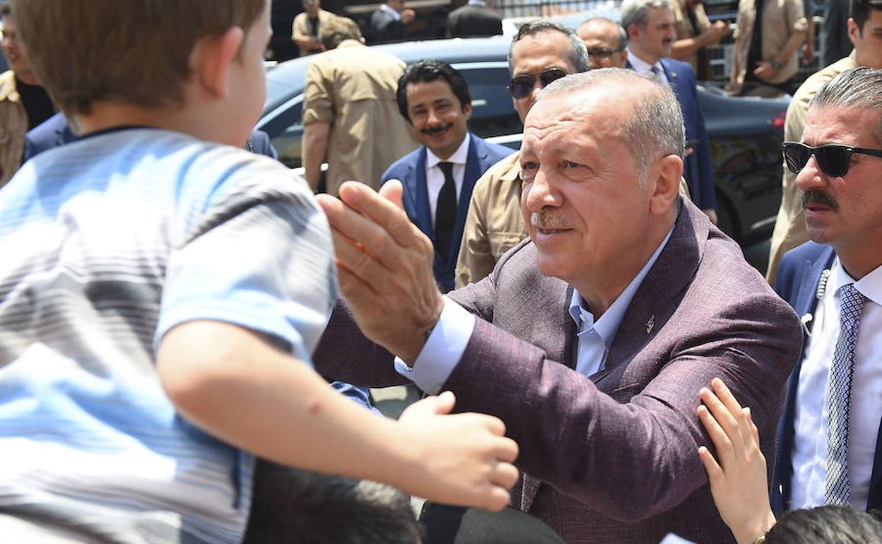 Erdogan se dispone a acariciar a un niño momentos antes de depositar el voto en el colegio electoral de Estambul.