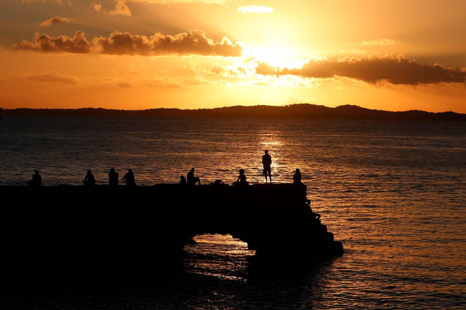 Varias personas ven la puesta de sol en el faro de la barra en Salvador (Brasil). 