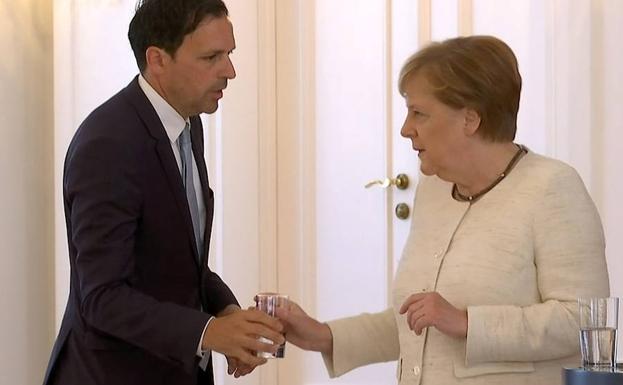 Merkel rechaza un vaso de agua de un asistente tras sufrir los temblores.