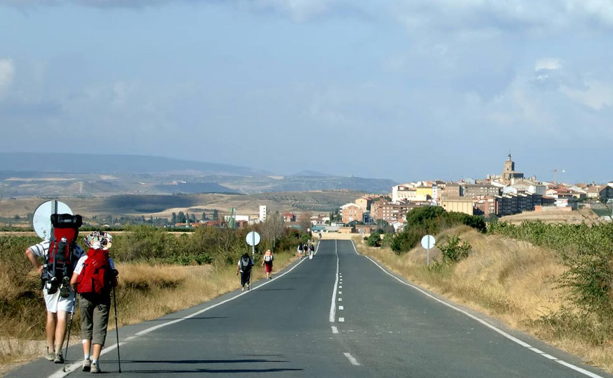 Peregrinos del Camino de Santiago se aproximan a Viana por el arcén de la carretera.