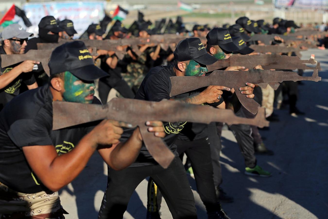 Jóvenes palestinos apuntan con rifles de madera durante una ceremonia de graduación de estilo militar en un campamento de verano organizado por el Yihad Islámico en la ciudad de Gaza
