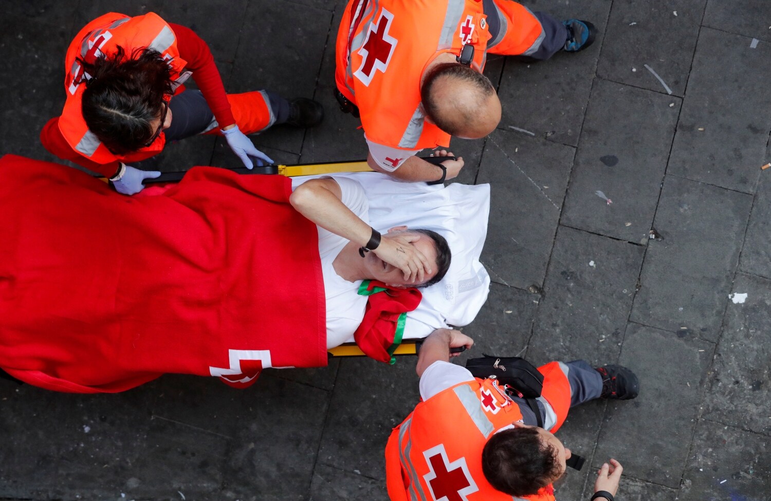 El personal médico ayuda a un corredor durante la corrida de los toros en el festival de San Fermín en Pamplona.