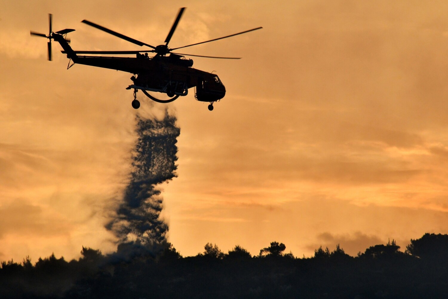 Un helicóptero descarga agua sobre el incendio forestal que se ha producido en el área de Agioi Theodoroi, en las afueras de la ciudad de Corinto, en el Peloponeso. 