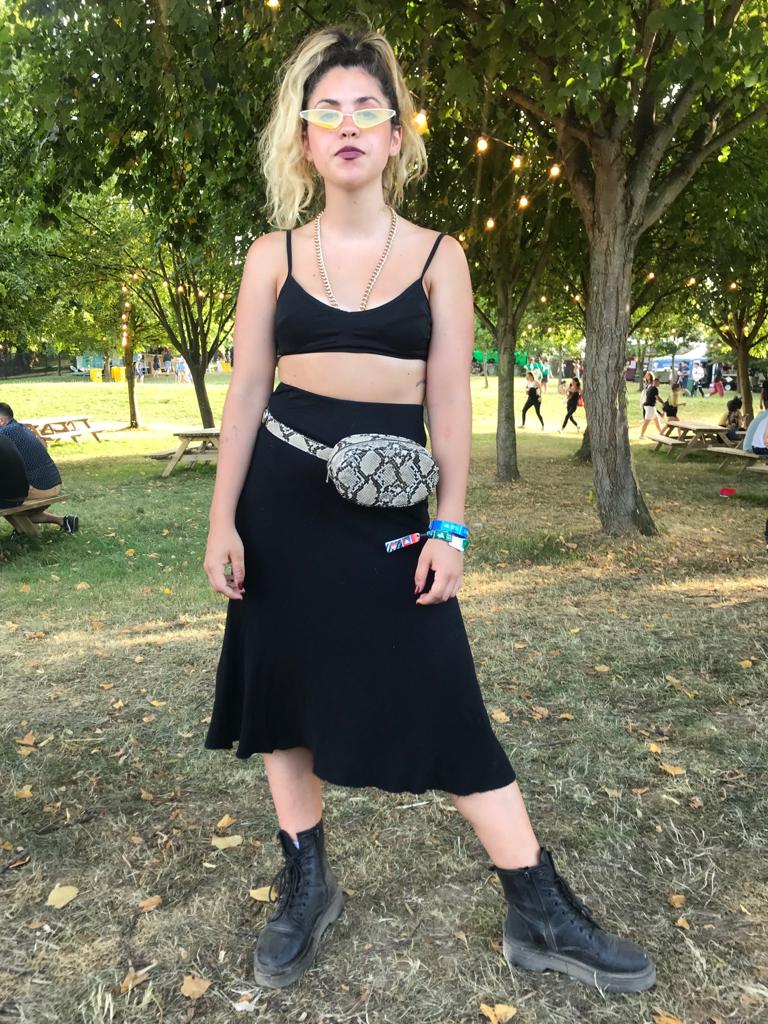 Claudia López visita el festival por primera vez con un look de estilo 'grunge' similar a los que lleva la artista catalana.El top es de Zara, el collar de eslabones dorados lo compró por Internet, la riñonera es de Pull & Bear y la falda de una tienda de segunda mano de la villa. Además, utiliza unas gafas de estética futurista que no faltan en el vestidor de Rosalía.