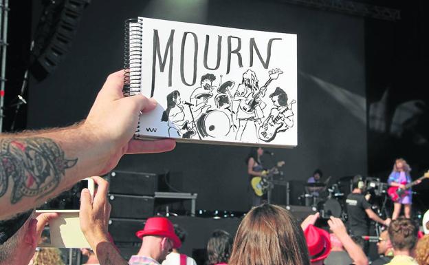 En primer plano, la ilustración del grupo Mourn, al fondo, el cuarteto sobre el escenario.