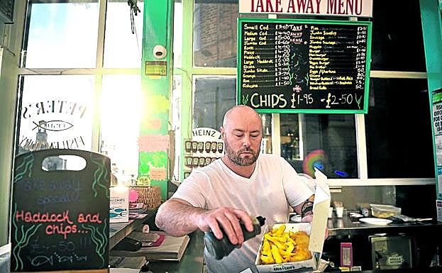 El encargado de un pub de Ramsgate, en Reino Unido, aliña con vinagre una ración de 'fish and chips'.